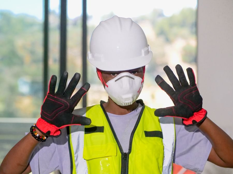 Trabajador usando equipo de protección personal completo, casco, guantes y mascarilla