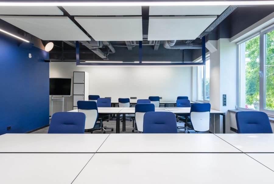 Escritorios blancos y sillas azules en espacio de trabajo moderno